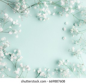 Floral composition with light, airy masses of small white flowers on turquoise blue background, top view, frame.  Gypsophila Baby's-breath flowers
