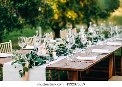 Floral garland of eucalyptus and pink flowers lies on the table for wedding reception. Italian dinner