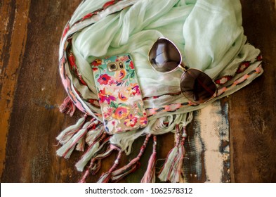 Floral Phone Case Sunglasses And Scarf On Wooden Table