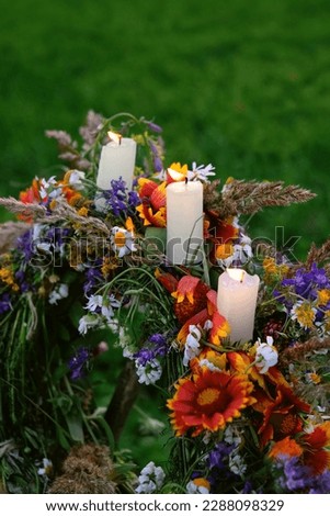 Floral wreath with burning candles on natural green blurred background. symbol of Summer Solstice Day, Midsummer, Litha sabbat. pagan folk tradition, wiccan ritual, witchcraft. mystery fairy scene