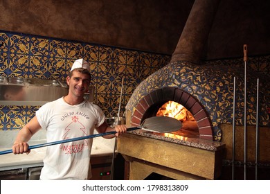 Florence, Italy - Aug 3, 2008:  Traditional Italian Wood Burning Pizza Oven With Man Holding A Pizza Peel Paddle At A Local Restaurant In  Florence, Italy