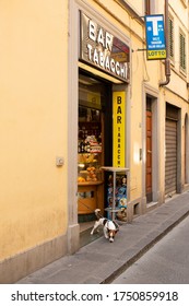 Florence, Italy, June 14, 2019: View Of A Small Brown And White Dog Sniffing The Footpath On The End Of Their Lead While Their Owner Is Inside A Small Cafe