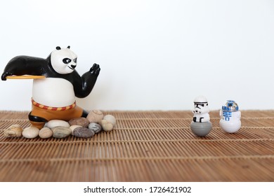 Florence (Italy) May 01 2020 - Kung Fu Panda Toy With Space Models On Bamboo Placemat And Pebbles On A White Background.