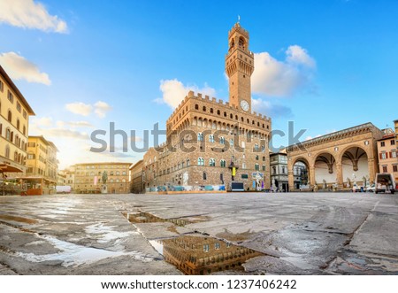 Florence, Italy. View of Piazza della Signoria square with Palazzo Vecchio reflecting in a puddle at sunrise