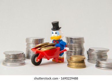 Florianopolis, Brazil, March 28, 2020: Lego Minifigure of Scrooge McDuck carrying coins on a wheelbarrow on white background. Selective focus. Lego minifigures are manufactured by The Lego Group.