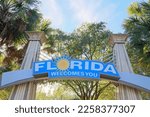 "Florida Welcomes You" Sign against palm trees and blue sky background