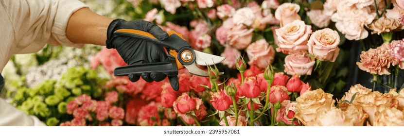 Florist in apron holding secateurs while cutting flowers in flower shop. High quality photo - Powered by Shutterstock