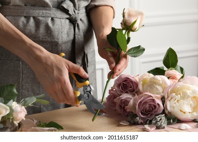 Florist cutting flower stem with pruner at workplace, closeup