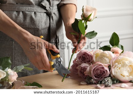 Florist cutting flower stem with pruner at workplace, closeup