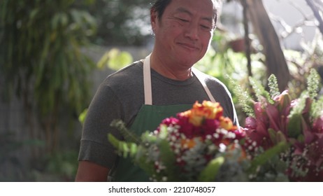 Florist Entrepreneur Holding Bouquet Of Flower Arrangement Ready For Customer Delivery. Male Asian Middle Age Entrepreneur Carries Colorful Roses