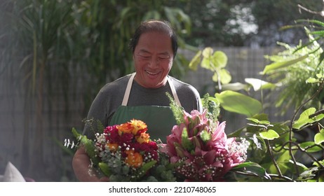 Florist Entrepreneur Holding Bouquet Of Flower Arrangement Ready For Customer Delivery. Male Asian Middle Age Entrepreneur Carries Colorful Roses