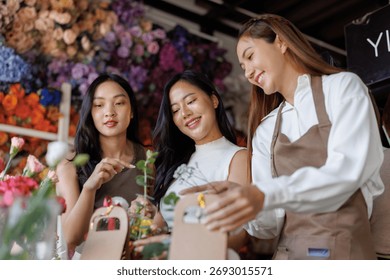 Florist explaining flower selecting and arranging to two smiling women. Learning floristry skills and enjoying creative workshop