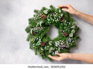 florist hands holding Christmas wreath with flowers, eucalyptus and cones. Christmas wreath workshop. top view. space for text - Shutterstock ID 2036951201