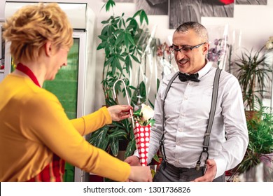 Florist Lady Showing Her Customer, Man In His 40's What Present To Buy For His Wife, Nut He's Not Sure If It's The One He Wants