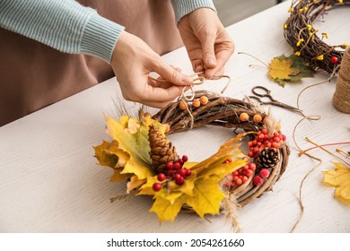 Florist making beautiful autumn wreath at table