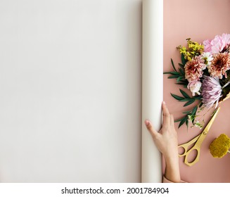 Florist Rolling Out A White Banner On A Pink Desk