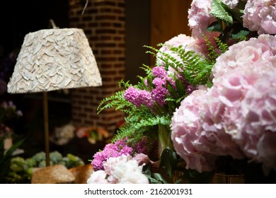 Florist Shop Window. Beautiful Decoration Of Luxurious Pink Hyacinth, Peony Flowers, Fern, Interior Items, Lighting. Showcase Window Of Floral Shop With Atmospheric Lights. Dark Exquisite Stage Photo