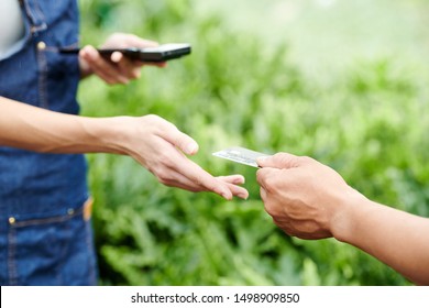 Florist taking credit card from hands of customer to accept payment for plants and flowers