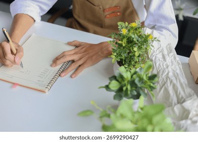 A florist  taking notes, making a list, planning for the shop order and inventory.