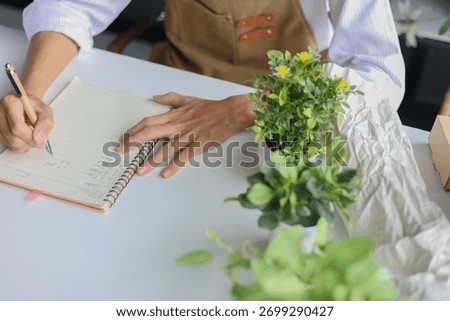 A florist  taking notes, making a list, planning for the shop order and inventory.