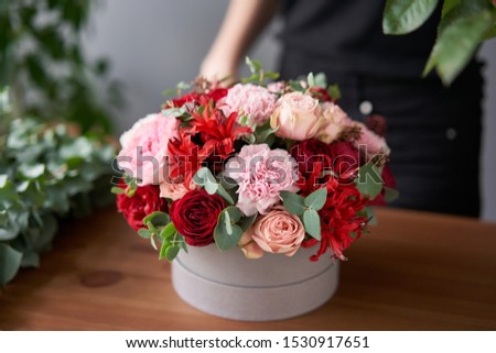 Florist woman creates flower arrangement in a round box. Beautiful bouquet of mixed flowers. Floral shop concept . Handsome fresh bunch. Flowers delivery
