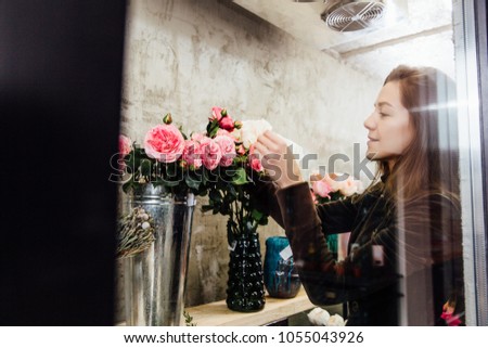 Florist woman on the work on flowers fridge background. Employee Arranges the bouquets on the shelves for storage.