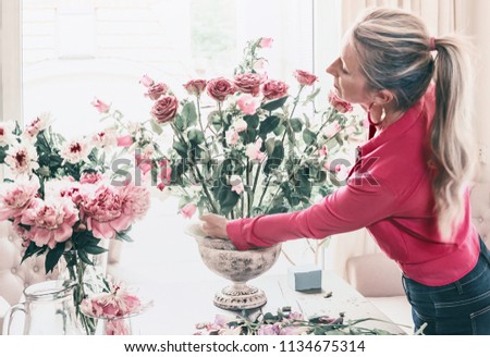 Similar – Woman arranges flower bouquet with roses in vase