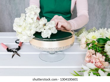 Florist At Work. How To Make Floral Decorations On Summer Party Table. Centerpiece With Rose, Dahlia And Hortensia Flowers. White Plates, Table Cloth, Romantic Wedding Reception. Step By Step, Diy. 