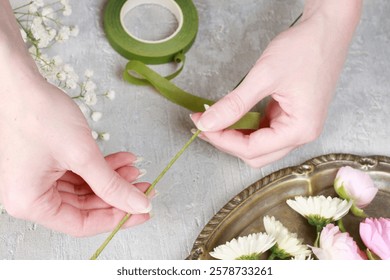 Florist at work. Steps of making wedding wreath with pink rose, ranunculus and white chrysanthemum. 