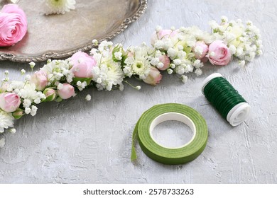 Florist at work. Steps of making wedding wreath with pink rose, ranunculus and white chrysanthemum. 