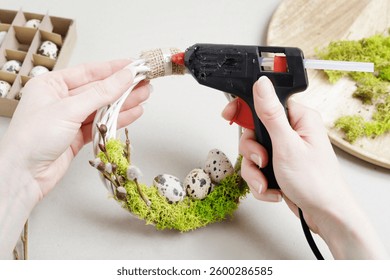 Florist at work: woman shows how to make traditional Easter door wreath with moss, quail eggs and catkins. Step by step, tutorial. 