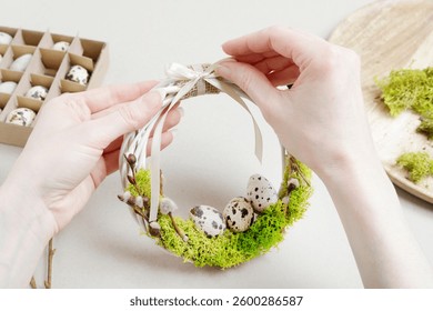 Florist at work: woman shows how to make traditional Easter door wreath with moss, quail eggs and catkins. Step by step, tutorial. 