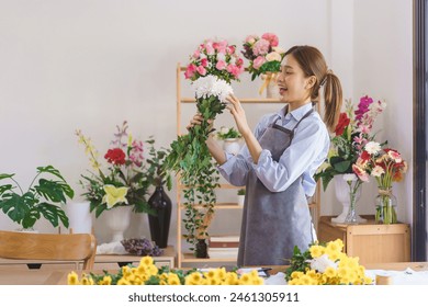 Floristry concept, Woman florist holding white chrysanthemum with smiling happiness in flower shop. - Powered by Shutterstock