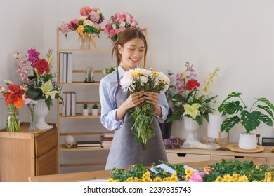 Floristry concept, Woman florist smiling and holding white and yellow chrysanthemum in flower shop. - Powered by Shutterstock