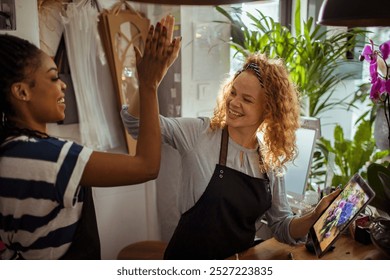 Florists giving a high-five while working together in flower shop - Powered by Shutterstock