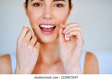 Floss that teeth. Cropped shot of a beautiful young woman flossing her teeth. - Shutterstock ID 2139872597