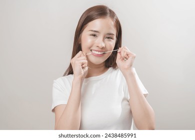 Flossing teeth, dental care hygiene concept, asian young woman flossing teeth with dental floss, smile happy with perfect white teeth, using tooth floss cleaning, healthy teeth isolated on background. - Powered by Shutterstock