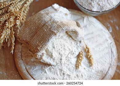 Flour in burlap bag on cutting board and wooden table background - Shutterstock ID 260254724
