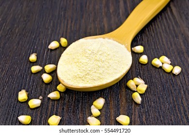 Flour corn in a spoon, maize grains on the background of dark wooden boards