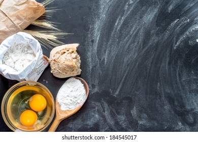 Flour, eggs, and cooking utensils on a wooden cutting board.