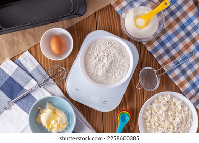 Flour on digital kitchen scale with cookie ingredients for baking on wooden table, weight 150 g - Shutterstock ID 2258600385