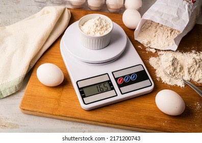 Flour on digital scale with cookie ingredients for baking on wooden table