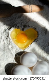 Flour On A Table With A Cookie Cutter In The Shape Of A Man And A Whisk For Kneading, Eggs. Pit In Flour In The Form Of A Heart Into Which An Egg Is Broken