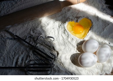 Flour On A Table With A Cookie Cutter In The Shape Of A Man And A Whisk For Kneading, Eggs. Pit In Flour In The Form Of A Heart Into Which An Egg Is Broken