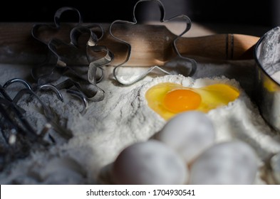 Flour On A Table With A Cookie Cutter In The Shape Of A Man And A Whisk For Kneading, Eggs. Pit In Flour In The Form Of A Heart Into Which An Egg Is Broken