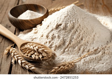 The  flour pile and wheat grains in wooden spoon and bowl on wooden background