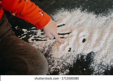 Flour Sensory Play for Toddlers. Easy flour sensory play activity for babies. Cute little girl sits on kitchen table and plays with flour.