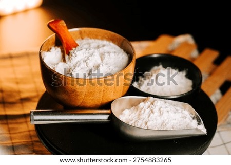 Flour surrounded by measuring tools on a kitchen counter with a soft glow in the background