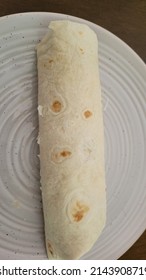 Flour Tortilla Wrapped Burrito On Glass White Plate