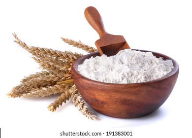 flour with wheat in a wooden bowl and shovel on a white background